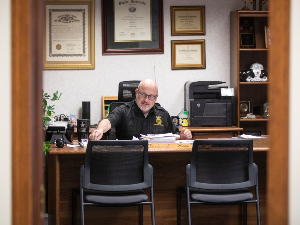 Darin Beck sits behind the desk in his office